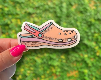May include: A pink and blue cartoon illustration of a clog shoe with a white background.