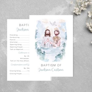 May include: Baptism invitation featuring a watercolor illustration of two figures in water, with a dove above. The text "Baptism of Jackson Carlson" is displayed in a soft blue font. A coordinating program card is also shown.