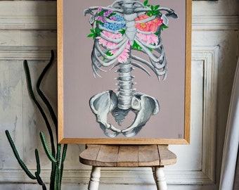 May include: A framed painting of a human skeleton with flowers growing inside the rib cage. The flowers are pink, purple, and white. The background is a light brown color.