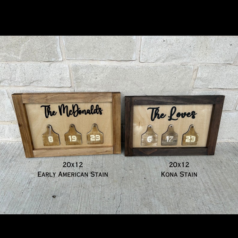 May include: Two wooden signs with the names "The McDonalds" and "The Loves" in black lettering. Each sign has three wooden tags with numbers on them. The sign on the left is stained in an Early American stain and the sign on the right is stained in a Kona stain. Both signs are 20 inches by 12 inches.