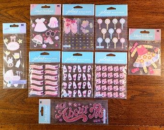 Könnte beinhalten: Ein Set mit zehn Blättern rosa, weiß und blauer Baby-Mädchen-Sticker. Die Sticker zeigen Bilder von Babyflaschen, Schnullern, Schleifen und die Worte "It's a Girl!" und "All About Me".