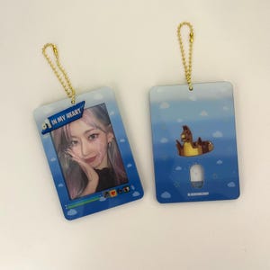 May include: Two rectangular keychains with gold-colored chain attachments. One keychain features a photo of a person with the text "IN MY HEART". The other keychain has a cartoon illustration of a horse in a pool float.