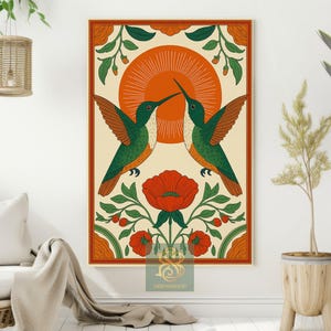 May include: A framed art print featuring two hummingbirds with green and orange plumage, facing each other. The birds are set against a cream background with an orange sunburst design. Red flowers and green foliage frame the birds.