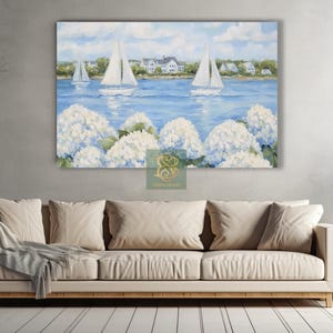 May include: A large canvas print depicting a serene coastal scene. White sailboats glide across a blue sea, with white houses lining the shore under a cloudy sky. White hydrangea flowers bloom in the foreground, adding a touch of nature.