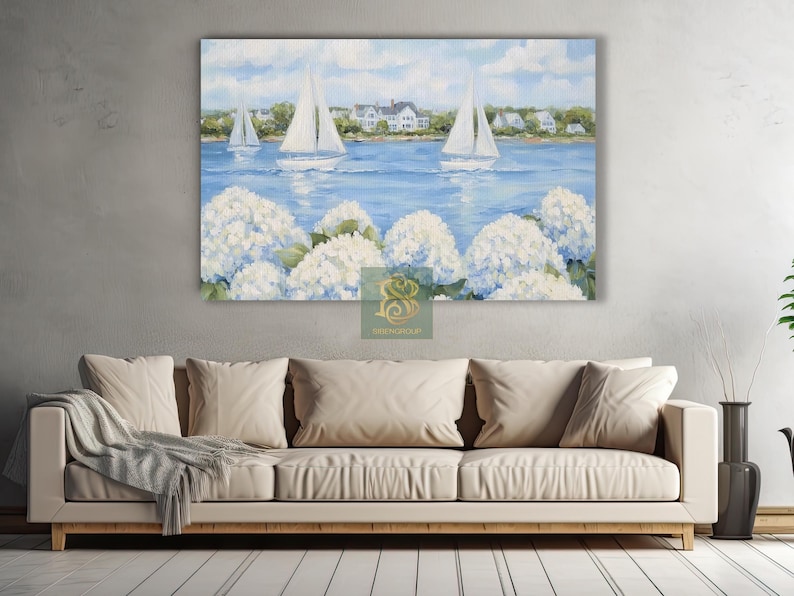 May include: A large canvas print depicting a serene coastal scene. White sailboats glide across a blue sea, with white houses lining the shore under a cloudy sky. White hydrangea flowers bloom in the foreground, adding a touch of nature.