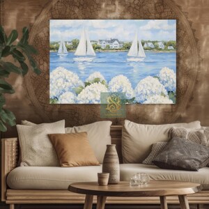 May include: A canvas print of a coastal scene featuring sailboats on a blue sea, white houses, and white hydrangea flowers. The artwork is displayed above a beige sofa with decorative pillows and a wooden coffee table.