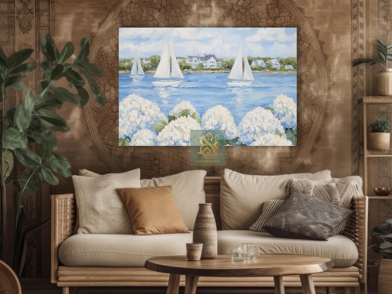 May include: A canvas print of a coastal scene featuring sailboats on a blue sea, white houses, and white hydrangea flowers. The artwork is displayed above a beige sofa with decorative pillows and a wooden coffee table.