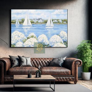 May include: A framed landscape painting depicts sailboats on a blue sea, with white hydrangeas in the foreground. The sky is blue with clouds, and houses are visible in the distance. The painting is displayed above a brown leather sofa.