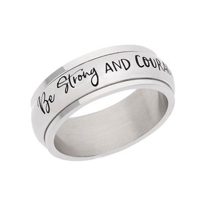 Puede incluir: Un anillo giratorio de plata con la inscripción "Sé fuerte y valiente" grabada en la banda.