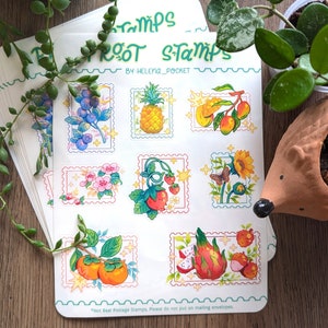May include: A sheet of colorful fruit themed stickers with the text "ROOT Stamps" and "BY: HELENA_POCKET". The stickers feature illustrations of various fruits, including pineapple, mango, strawberries, dragon fruit, and persimmons. The text at the bottom reads "*Not Real Postage Stamps, Please do not put on mailing envelopes."