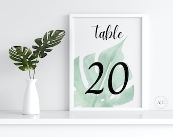 May include: A white frame with a green watercolor leaf design and the text "Table 20" in black font.