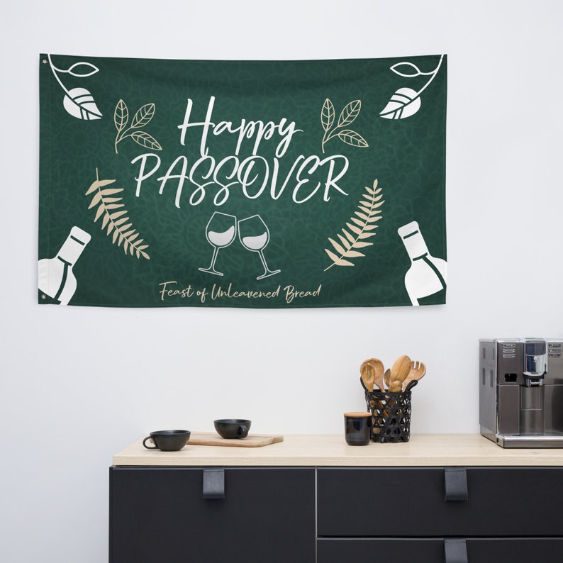May include: Green banner with white text that reads "Happy Passover Feast of Unleavened Bread". The banner also features two wine glasses clinking, a bottle of wine, and leafy branches.