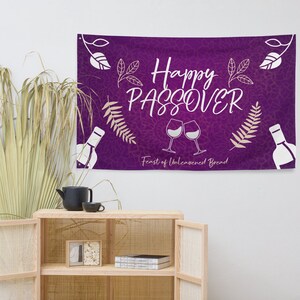 May include: Purple banner with white text saying 'Happy Passover' and a white illustration of two wine glasses and a bottle. The banner has a brown and white floral pattern and the text 'Feast of Unleavened Bread'.