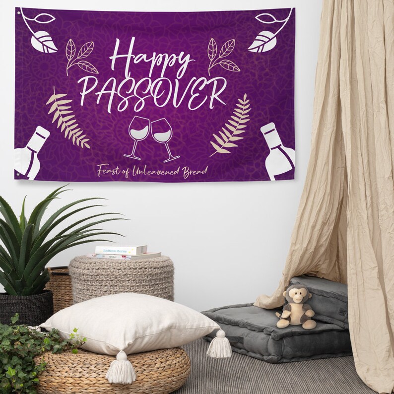 May include: Purple banner with the text "Happy Passover Feast of Unleavened Bread" in white lettering. The banner also features two wine glasses and two bottles of wine, all in white.