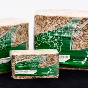 May include: Three blocks of brown sphagnum moss, packaged in clear plastic bags with green labels. The labels feature a white orchid design and the text "One Mile Moss Limited, New Zealand". The largest block is labeled "1KG" and the smallest block is labeled "150g".