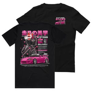 May include: Black t-shirt with a pink Honda S2000 car graphic and Japanese text. The design includes a stylized illustration of a person wearing a fox mask and cherry blossom accents. The shirt has the text "Honda S2000" and "JBM".
