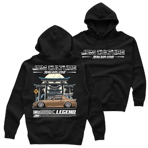 Op de afbeelding: Zwarte hoodie met een witte grafische print van een rode Honda S2000 sportwagen voor een Japanse tempel. De tekst "JDM Culture - Japan Auto Scene" en "S2K Legend" staat op de hoodie gedrukt.