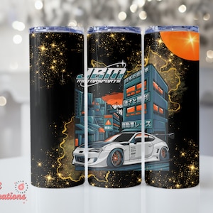May include: A white car with a black and orange design on a black background with gold stars. The car is driving through a city with Japanese text on the buildings. The text on the car says "JBM MOTORSPORTS".