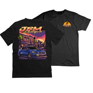 May include: Black t-shirt with a blue car and cityscape graphic on the back. The front of the shirt has a small graphic with the text "JRM Motorsports".