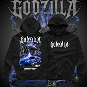 May include: Black hoodie with the word "Godzilla" in white, stylized lettering. The back features a graphic of Godzilla, a blue sports car, and the text "JDM MOTORSPORTS". The design incorporates blue and purple lightning effects, with Japanese text.