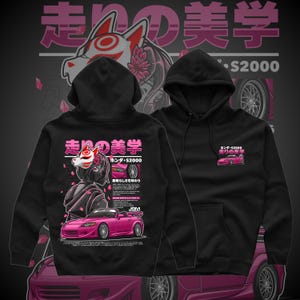 May include: Black hoodie featuring a pink sports car graphic with Japanese text and a stylized fox mask design. The hoodie includes the text "S2000" and "JBM" on the front and back, with additional Japanese characters.