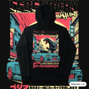 May include: Black hoodie featuring a graphic print of a blue car, a Godzilla-like monster, and Japanese text. The text reads "Legendary Skyline" and "JBM Motorsports".