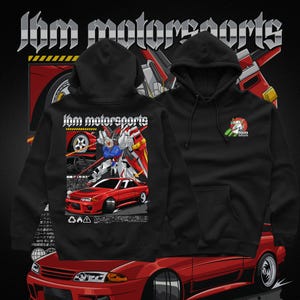 May include: Black hooded sweatshirts with the text "Jbm motorsports". One sweatshirt features a red car graphic and a robot. The other has a small logo. The background is black with red car details.