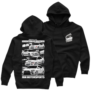 May include: Black hoodie featuring a white graphic of four generations of Mitsubishi Lancer Evolution cars. The graphic includes the text "Generations of Greatness" and "Turbo Tribe".