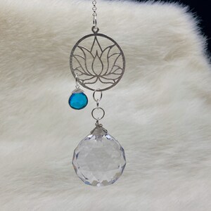 May include: A silver lotus flower charm with a clear crystal ball and a turquoise gemstone hanging from it.