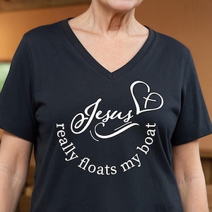 May include: Black V-neck t-shirt with the text "Jesus really floats my boat" in white script and a heart-shaped design. The shirt is made of a soft material and is suitable for casual wear.