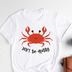 May include: White t-shirt with a red cartoon crab and the text "Don't be crabby".