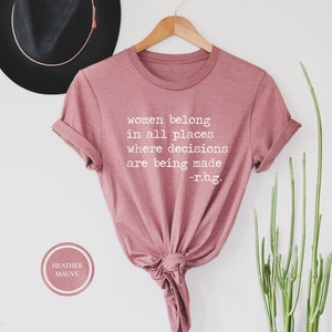 May include: A heather mauve t-shirt with the text "women belong in all places where decisions are being made -r.b.g." printed in white.