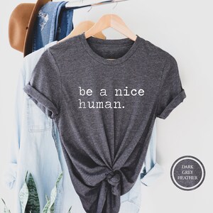 Pu&ograve; includere: Maglietta grigio scuro melange con la scritta "be a nice human." stampata in bianco.