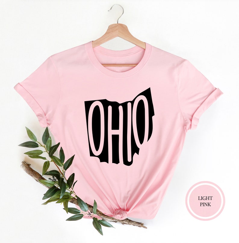 May include: A light pink t-shirt with a black outline of the state of Ohio and the word "OHIO" written inside the outline.