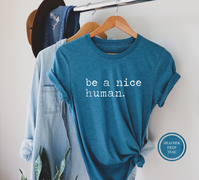 Pu&ograve; includere: Una maglietta blu turchese con la scritta "be a nice human." stampata in bianco sul davanti.