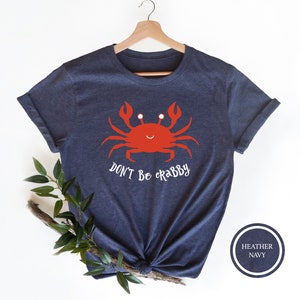 May include: A navy blue t-shirt with a red cartoon crab and the text "Don't be crabby".