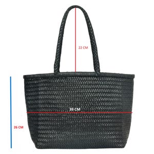 Puede incluir: Bolso tote negro tejido con asas trenzadas. El bolso mide 26 cm de alto, 39 cm de ancho y las asas tienen una caída de 22 cm. El bolso tote está hecho de un material tejido.