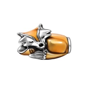 Puede incluir: Un charm de zorro plateado y naranja en posición de dormir. El zorro tiene cabeza y patas plateadas, con cuerpo naranja. El charm está detallado con nariz negra y ojos cerrados. Adecuado para pulseras y collares.