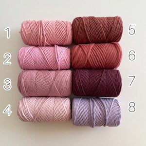 May include: Eight spools of cotton cord in various shades of pink, red, and purple. The spools are numbered 1 through 8.