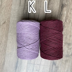 May include: Two spools of cotton rope, one lavender and one burgundy. The spools are labelled "K" and "L".