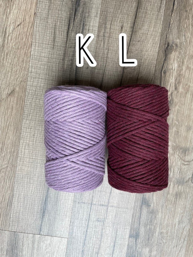 May include: Two spools of cotton rope, one lavender and one burgundy. The spools are labelled "K" and "L".
