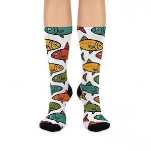 May include: A pair of knee-high socks featuring a repeating pattern of colorful cartoon fish. The fish are in shades of yellow, orange, red, green, and teal, set against a white background. The socks have black heels and toes.
