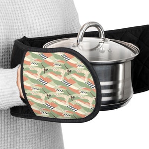 May include: A black oven mitt with a colorful geometric pattern. The mitt is designed to protect hands from heat while handling hot pots and pans.