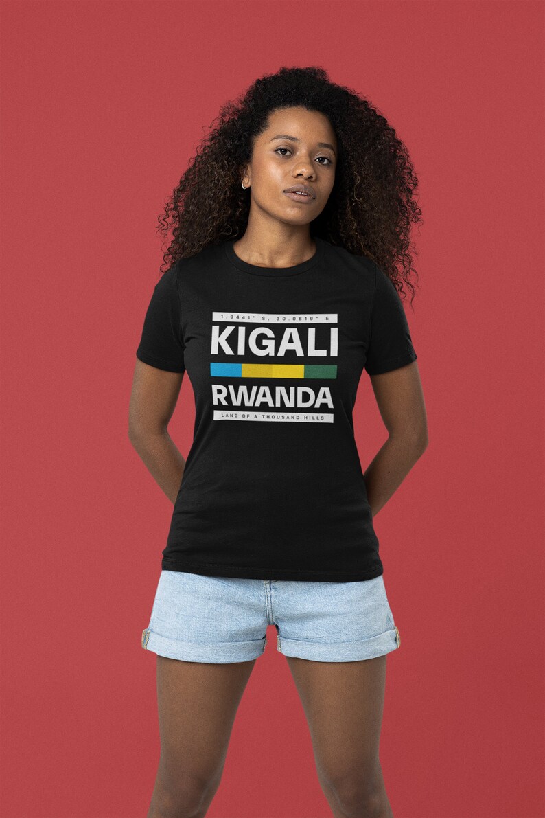 May include: A black t-shirt with white text that reads "KIGALI RWANDA LAND OF A THOUSAND HILLS" with the Rwandan flag colors in a stripe above the word "RWANDA".