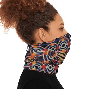 May include: A black neck gaiter with a colorful geometric pattern featuring circles, lines, and dots in shades of red, yellow, blue, and white. The neck gaiter is worn by a person with curly brown hair.