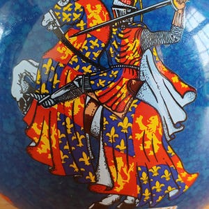 May include: A blue decorative object featuring a knight on horseback, rendered in red, yellow, and blue heraldic designs. The knight is holding a sword, and the object has the text "of Woodstock" at the bottom.