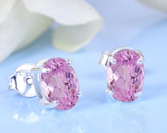 May include: A pair of silver stud earrings with oval-shaped pink gemstones.