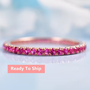 Könnte beinhalten: Ein zarter Ewigkeitsring mit einer Reihe von rosa Saphiren, die in eine Roségold-Band gefasst sind.