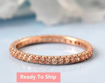 May include: A delicate rose gold eternity band with a row of small, sparkling champagne diamonds.