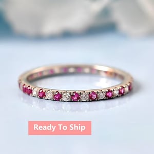 Puede incluir: Un delicado anillo de eternidad con piedras de rubí y diamante alternas. El anillo está engastado en una banda de metal pulido.